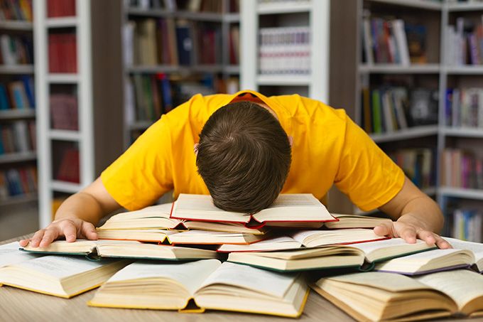 Coursera học cách học: một học sinh gục đầu vào đống sách.