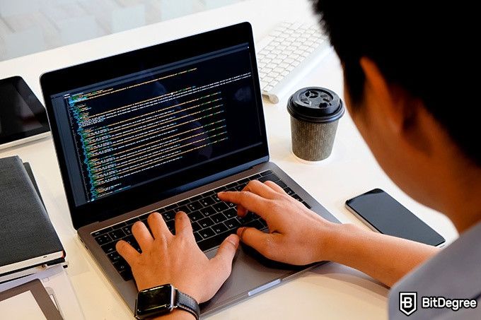 Curso de Python MIT: Hombre escribiendo código en laptop.