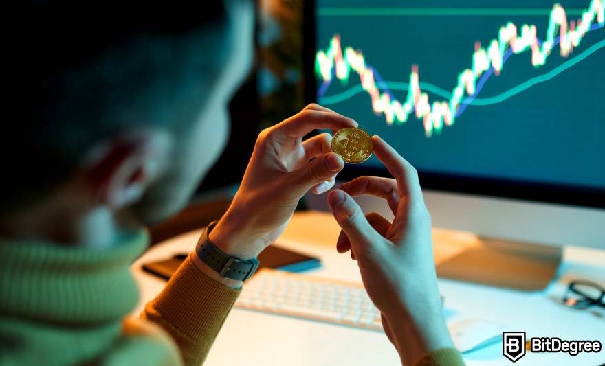 Best crypto trading course: a man is holding and looking at a physical Bitcoin coin.