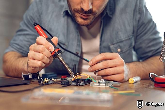 Online engineering degree: a man is working on a circuit board.