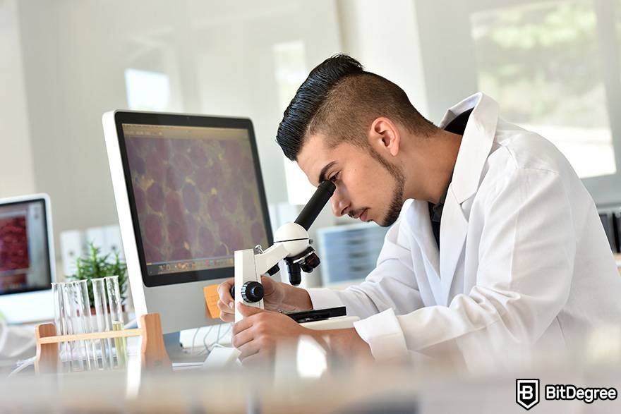 Online biology courses: a man is looking through a microscope.