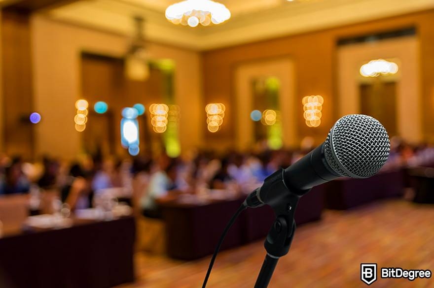 Public speaking classes online: a microphone stand is placed in front of an audience.