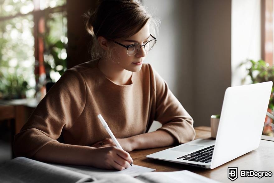 Where to learn ChatGPT: a woman is studying on her laptop and taking notes.